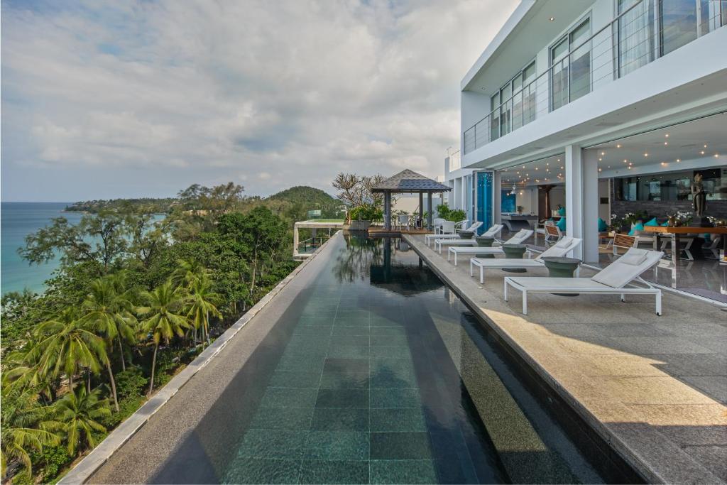 an outdoor swimming pool with lounge chairs and the ocean at Bluesiam Villa - SHA Certified in Surin Beach
