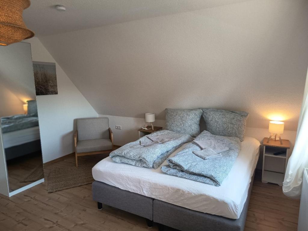a bedroom with a bed with pillows and a chair at Haus Lützowallee in Aurich
