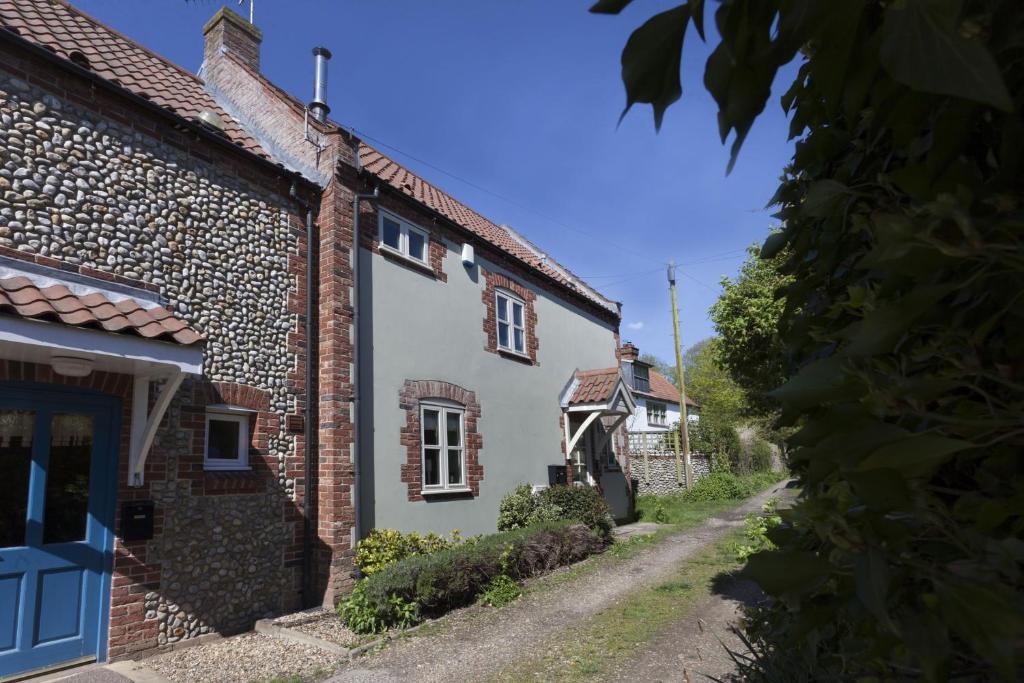 a white house with a blue door on a street at Legion Cottages in Blakeney