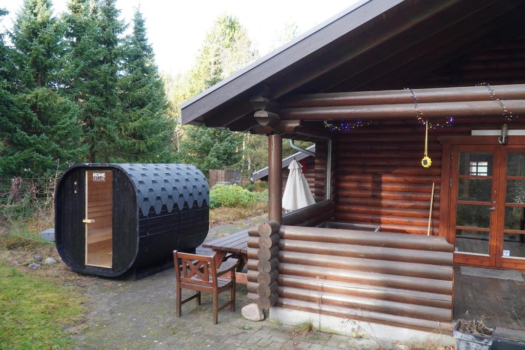 a wooden cabin with a large grill on the porch at The Log Cabin in Hadsund
