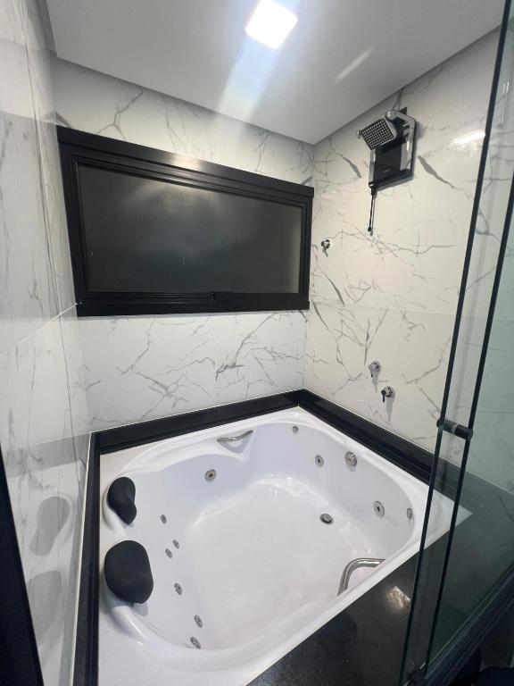 a bath tub in a bathroom with a glass wall at Suíte completa com cozinha e hidromassagem in Torres