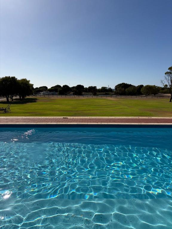 a pool of blue water with a field in the background at Wonnerup Beach Manor in Wonnerup