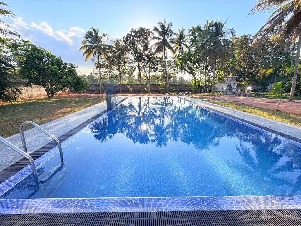 a swimming pool with blue water and palm trees at Singha Holiday Bungalow in Ibbagomuwa