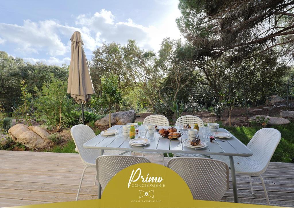 a table with chairs and an umbrella on a patio at Casa 115 - Plage & piscine chauffée in Pianottoli-Caldarello