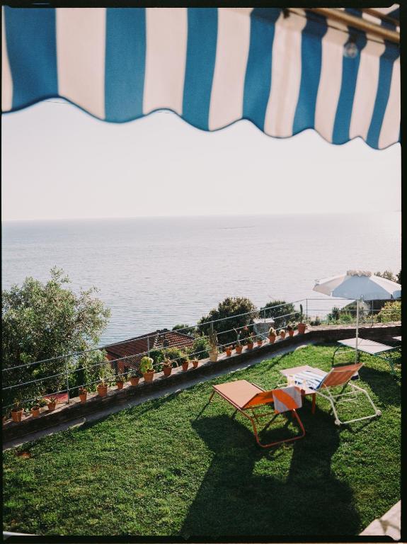 a patio with chairs and an umbrella and the ocean at Casa Pernice in Lavagna