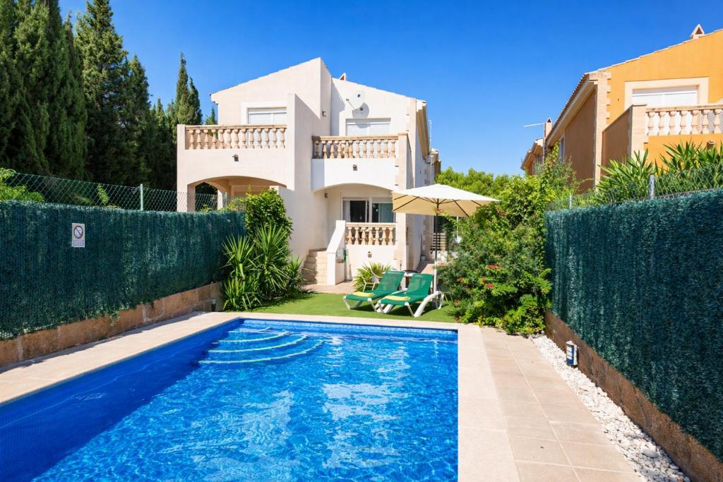 a villa with a swimming pool in front of a house at Villa El Olivo in Pollença