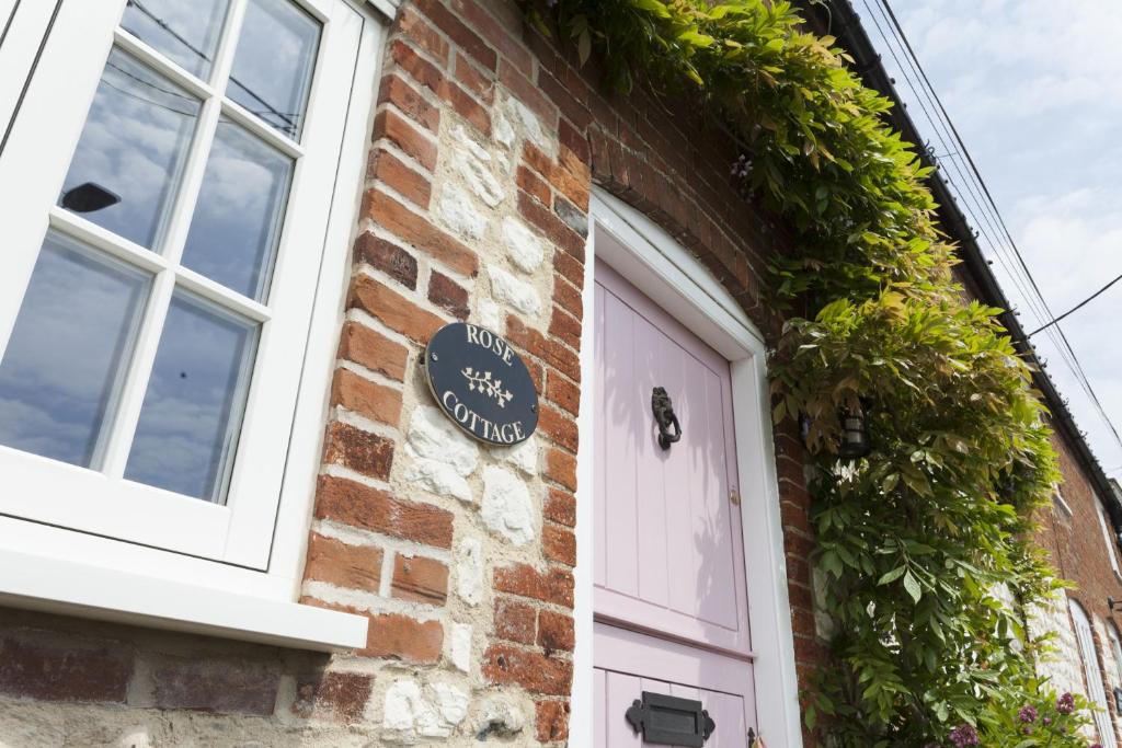 a brick building with a door and a sign on it at Rose Cottage in Burnham Thorpe