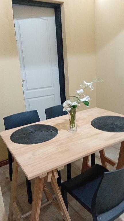 a wooden table with two chairs and a vase of flowers at Lo de Lety in Baradero