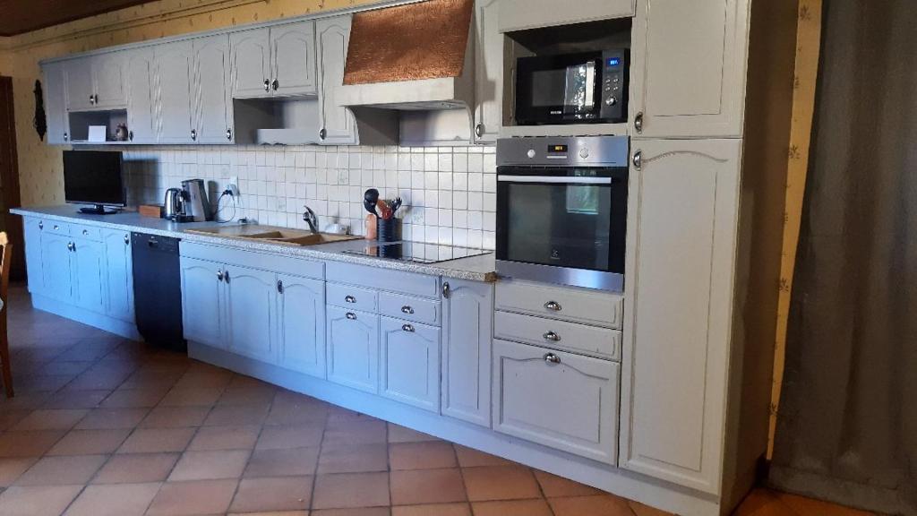 a kitchen with white cabinets and white appliances at Dépendance du Duesmois in Fontaines-en-Duesmois