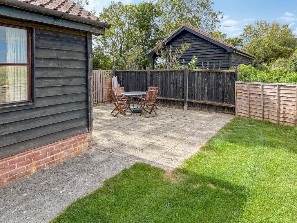 a patio with a table and chairs next to a fence at Rose Chalet in Framlingham