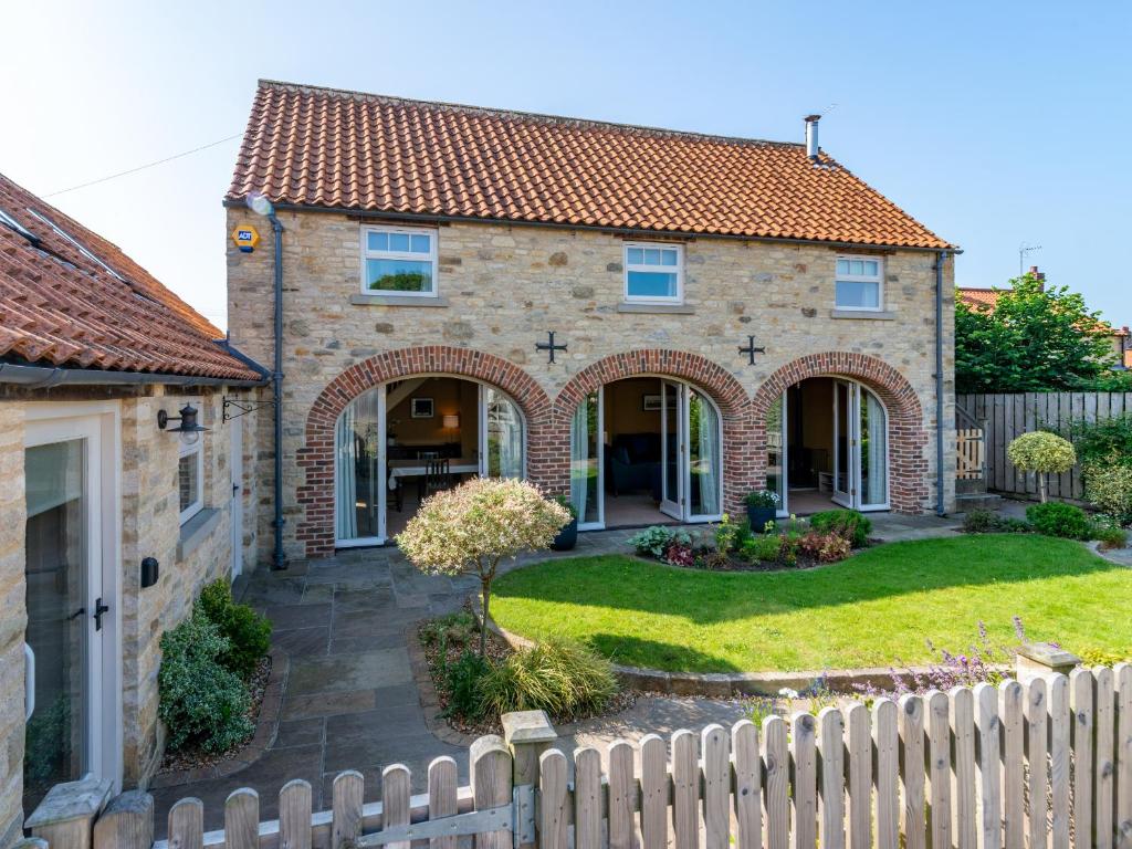 a brick house with a fence in front of it at The Cart House in Helmsley