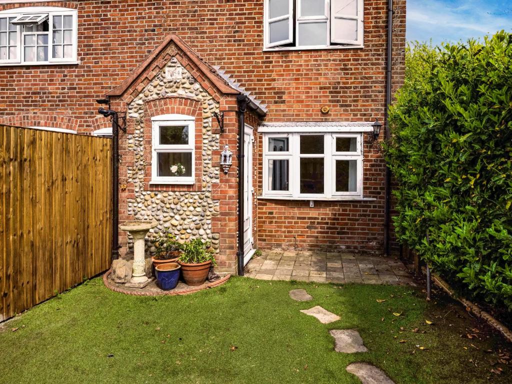 a small yard in front of a brick house at Painter's Cottage in Hemsby
