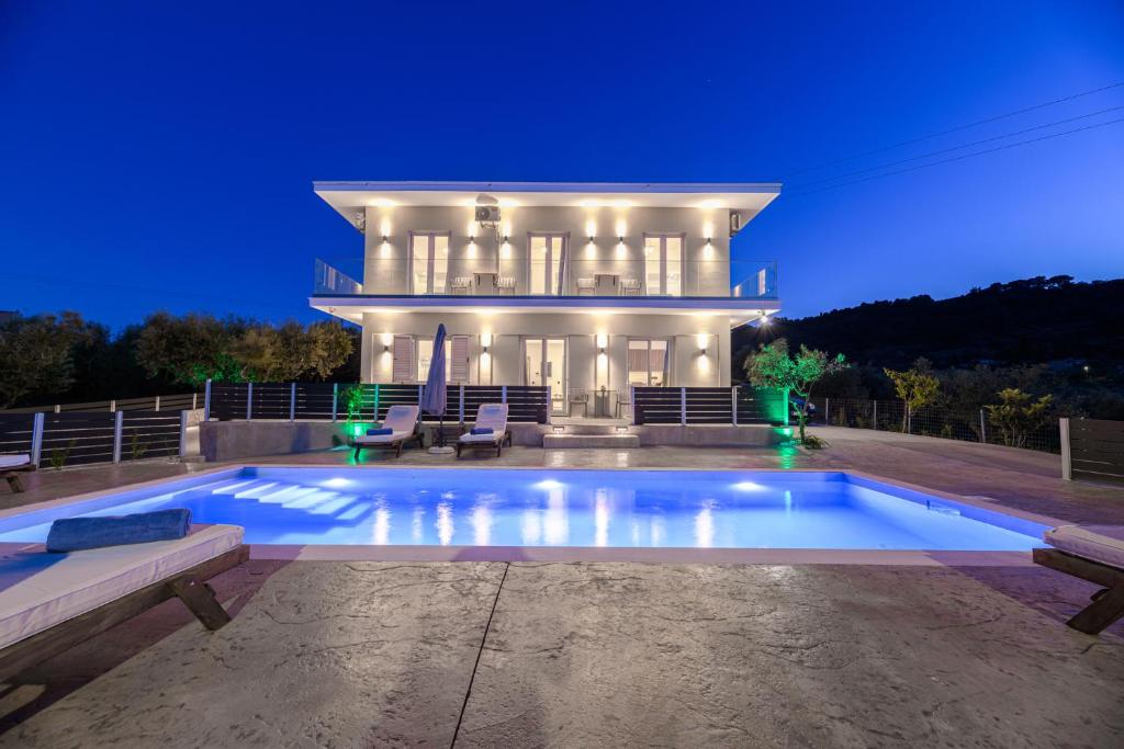 a house with a swimming pool in front of it at Athenia Apartments in Vasilikos