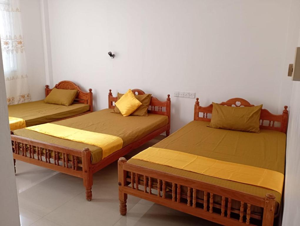 two beds in a room with yellow pillows on them at Wings Hotel & Hostel in Trincomalee