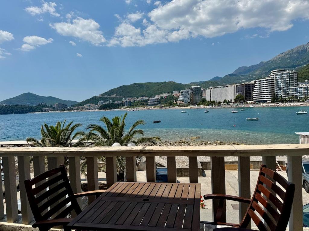 a wooden table and chairs on a balcony overlooking a beach at Lighthouse Rafailovići, Budva in Rafailovici