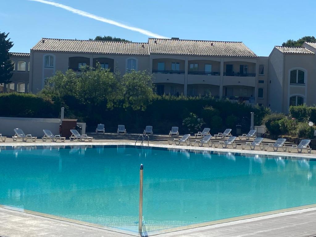 a large swimming pool with chairs and a building at Studio Rez de jardin coté piscine - Clim in Saint-Raphaël