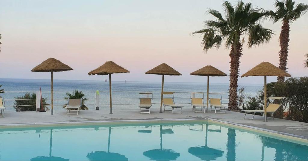 ein Schwimmbad mit Liegestühlen und Sonnenschirmen und das Meer in der Unterkunft Pescasubacquea in Crotone