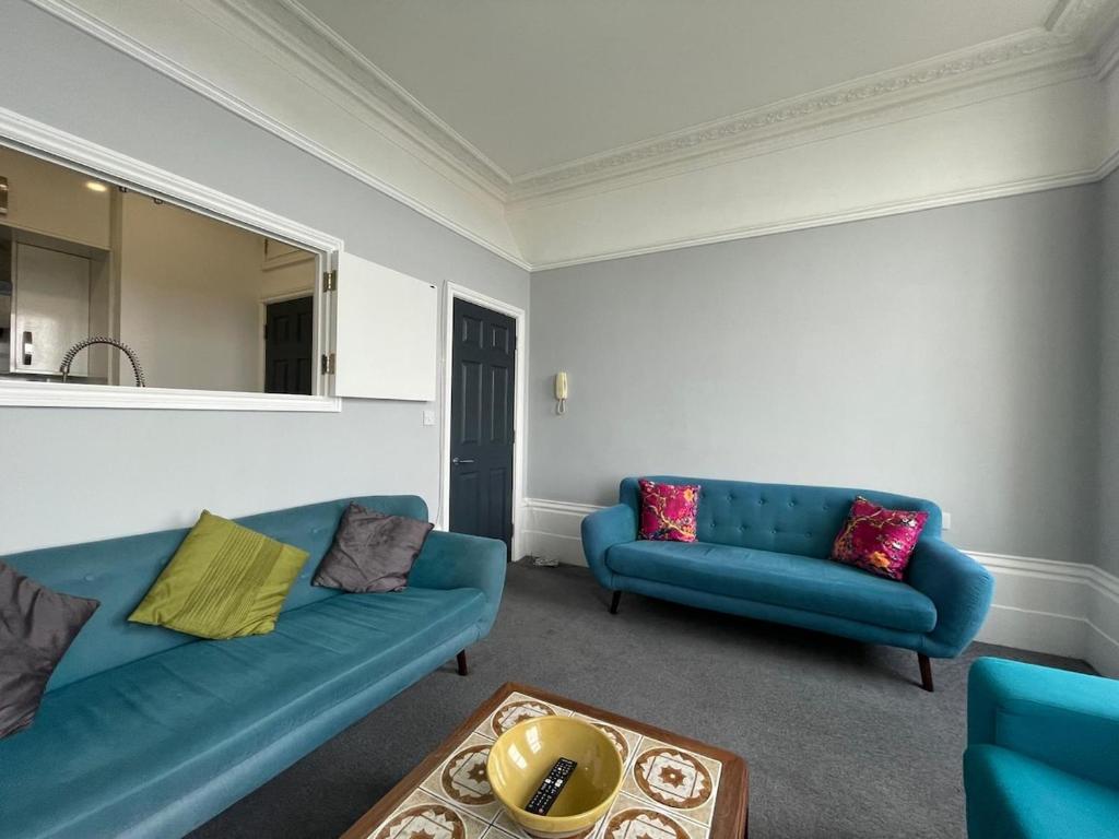 a living room with two blue couches and a table at Pier View 2 Bedroom Apartment in Herne Bay
