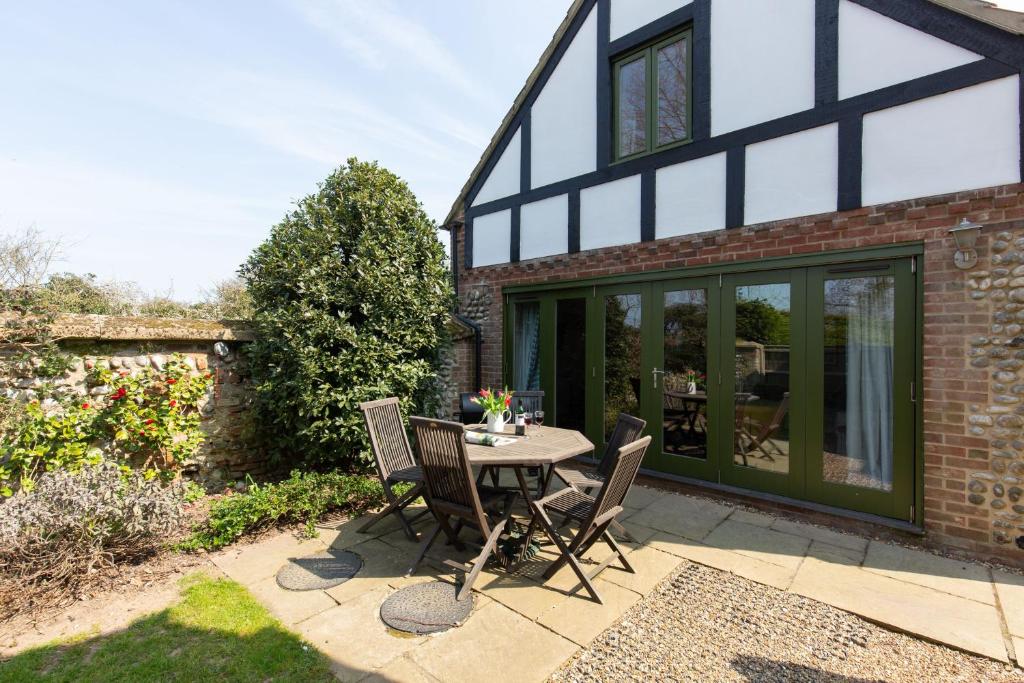 a patio with a table and chairs in front of a house at Riding Stable, Rookery Farm in West Beckham