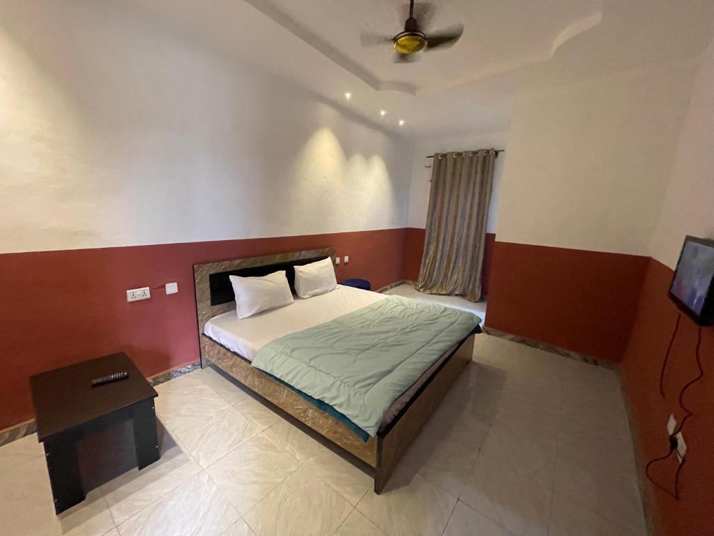 a small bedroom with a bed and a table at FE Purple Gold Hotel in Abuja