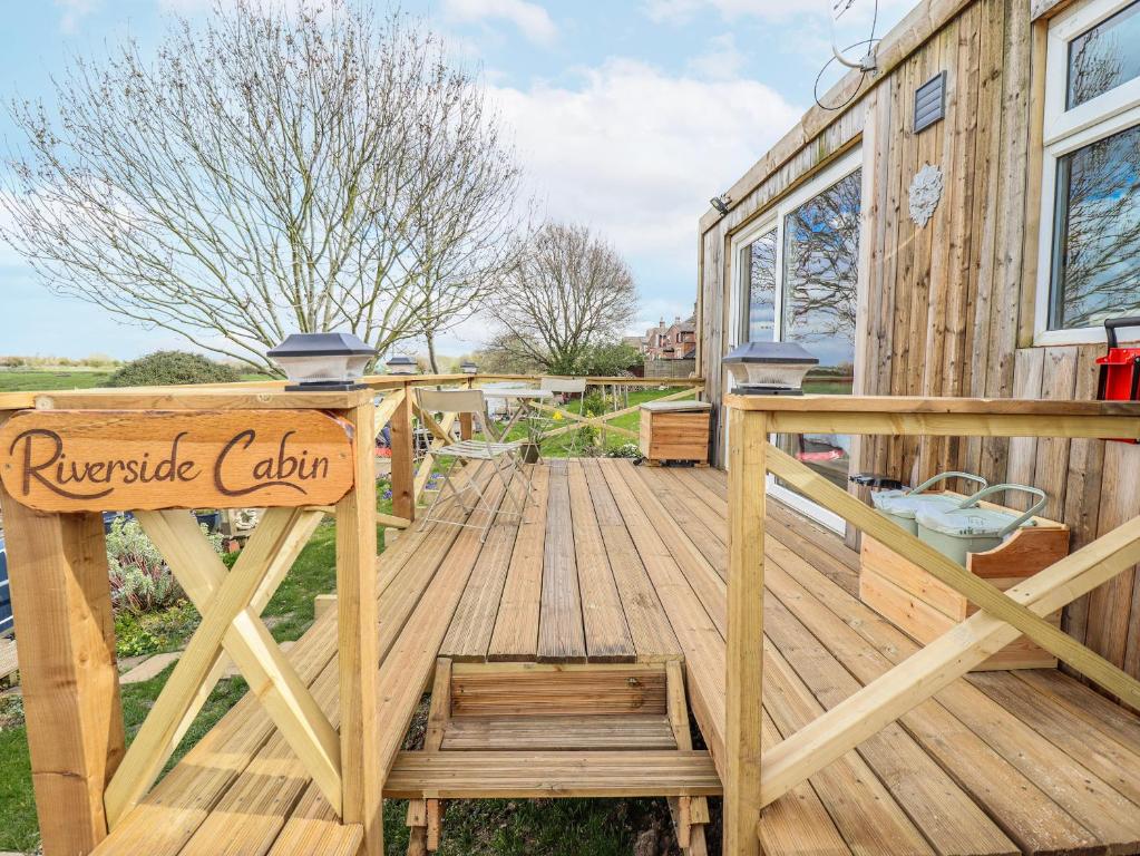 a wooden deck with a sign on a house at Riverside Cabin in Peterborough