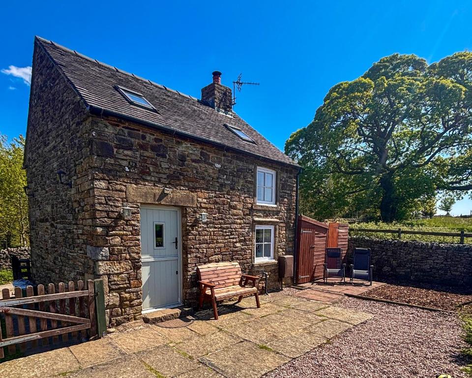 a small stone house with a man on top of it at School House Cottage in Buxton