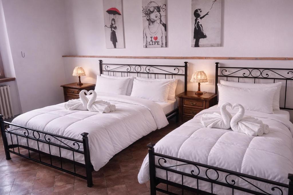 two beds in a bedroom with white sheets and bows at 2ª Casa del Borgo Antico in Poggibonsi
