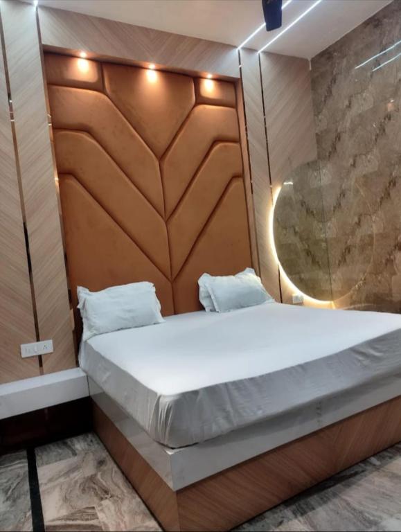 a bed in a room with a wooden headboard at Shraddha Hotel in Alīgarh