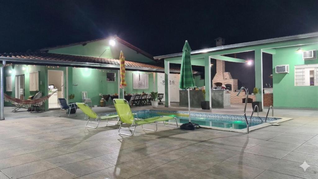 a house with a swimming pool and some chairs at Chácara Recanto do Sossego in Araçoiaba da Serra