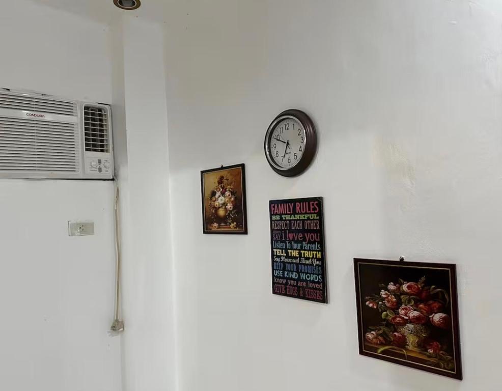 a wall with a clock and pictures on it at Private Room at MA Compound in Concepcion