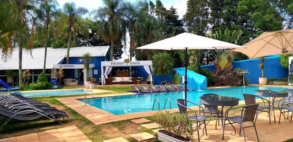 a pool with chairs and tables and an umbrella at Villa Verde Hotel Avaré in Avaré