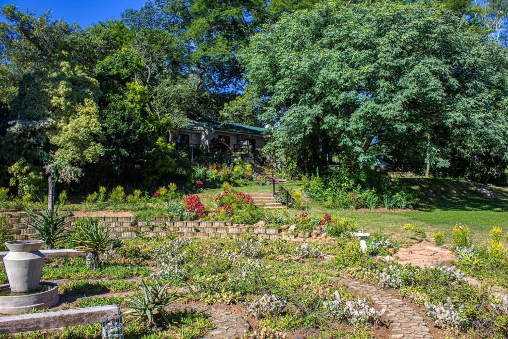 a garden with flowers and a house in the background at Kruger's Rest Guest House in Hazyview