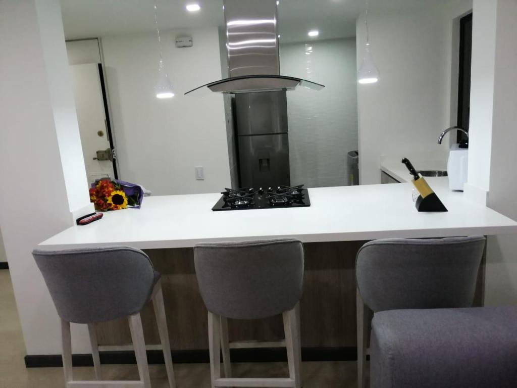 a kitchen with a white counter and some chairs at Nova MSuites Viveiro in Viveiro