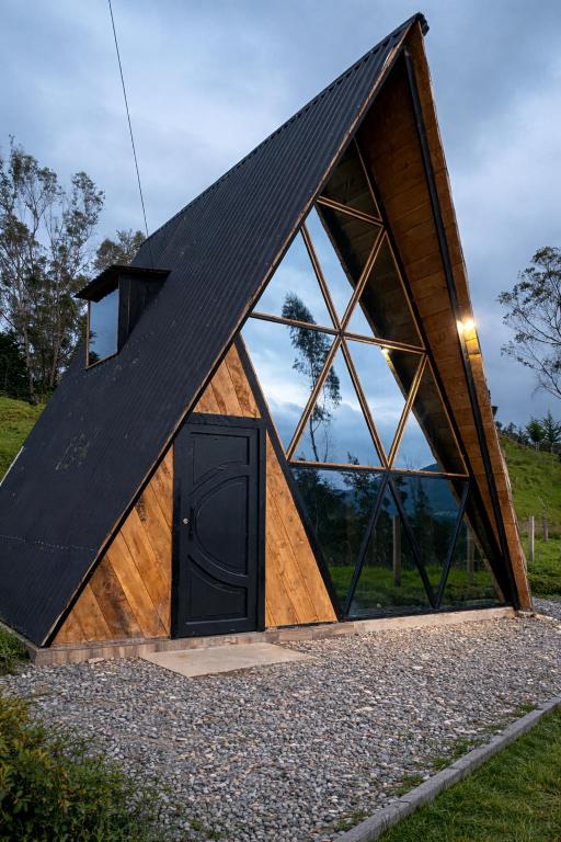 a small house with a triangular roof and a door at Chalet - Laguna de la Cocha in Pasto