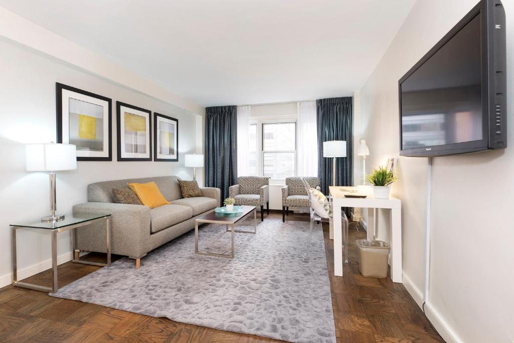 sala de estar con sofá y TV de pantalla plana en Murray Hill East Suites en Nueva York
