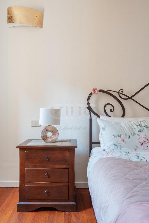 a bedroom with a bed and a wooden nightstand with a lamp at La Corte del Duca in Modena