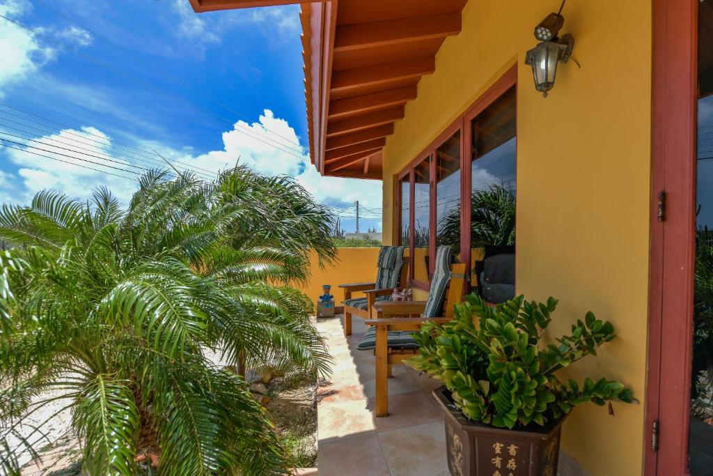 a yellow house with palm trees and a patio at Arantxa Residence in Noord