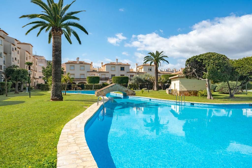 a large swimming pool with a palm tree and buildings at Casa Tucan Javea, luxury close to Arenal Beach in Jávea