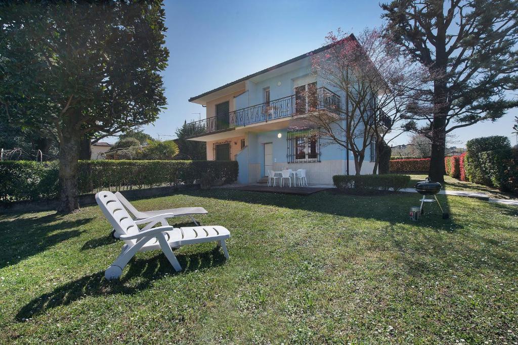 a white bench sitting in the grass in front of a house at Villa Iconi Lake Garda in Manerba del Garda