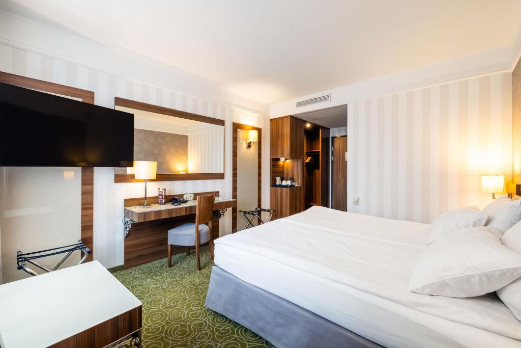 a hotel room with a large bed and a desk at Hotel Lord - Warsaw Airport in Warsaw