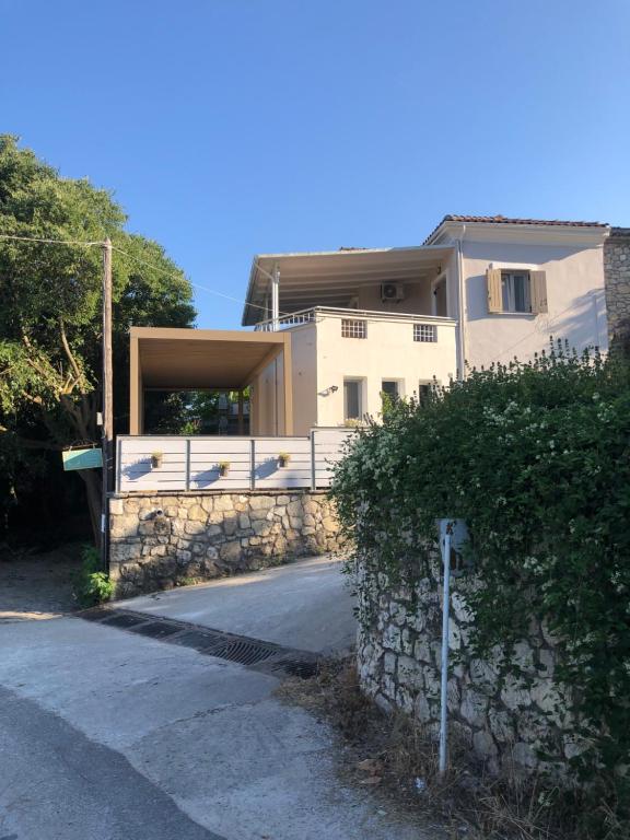 a house with a stone fence next to a street at Lemonaki House Lefkada in Asprogerakata