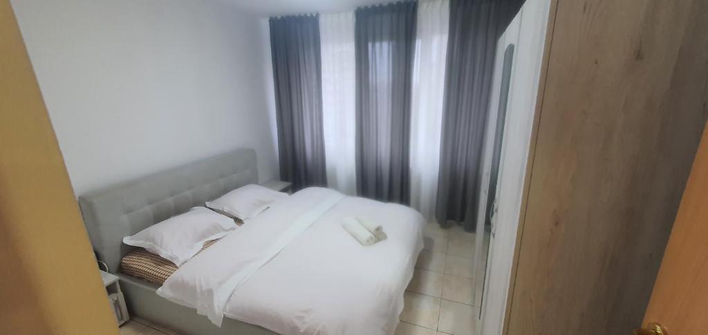 a bed with white sheets and pillows in a room at 5th Floor Oasis 2 Badroom Apartment in Bucharest