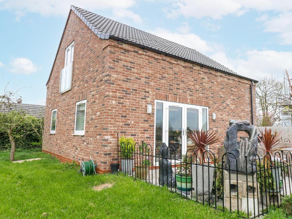 a brick house with a fence in the grass at The Retreat in Goole