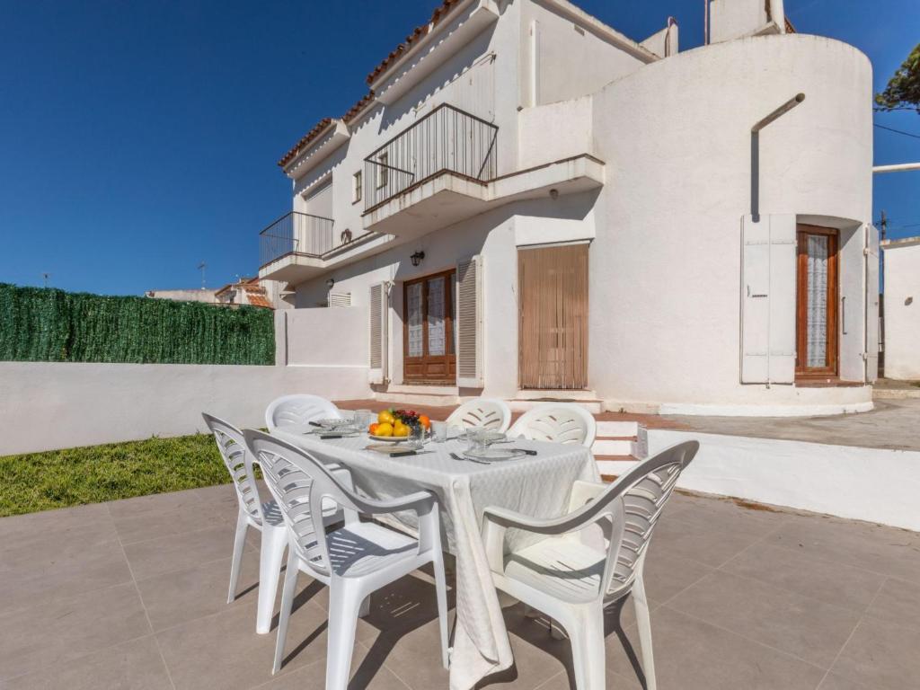 a white dining table and chairs in front of a white house at Holiday Home L'Escapade by Interhome in L'Escala