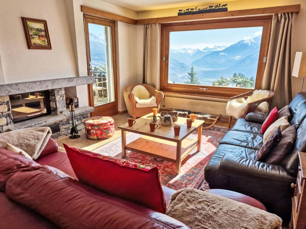 a living room with a couch and a large window at Chalet Chalet Aglaia by Interhome in Crans-Montana