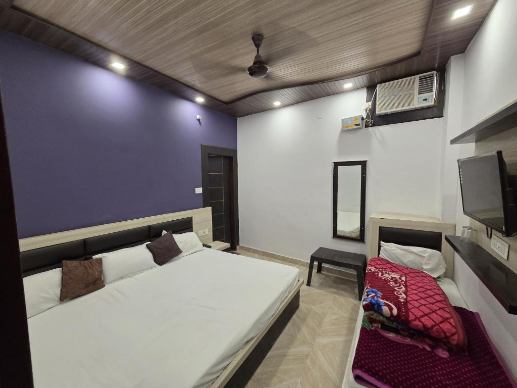 a bedroom with a large white bed and a tv at Hotel Sanwariya Palace in Haridwār