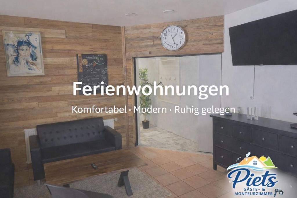 a living room with a couch and a clock on a wall at Piets Monteurwohnung Sandstedt in Hagen im Bremischen