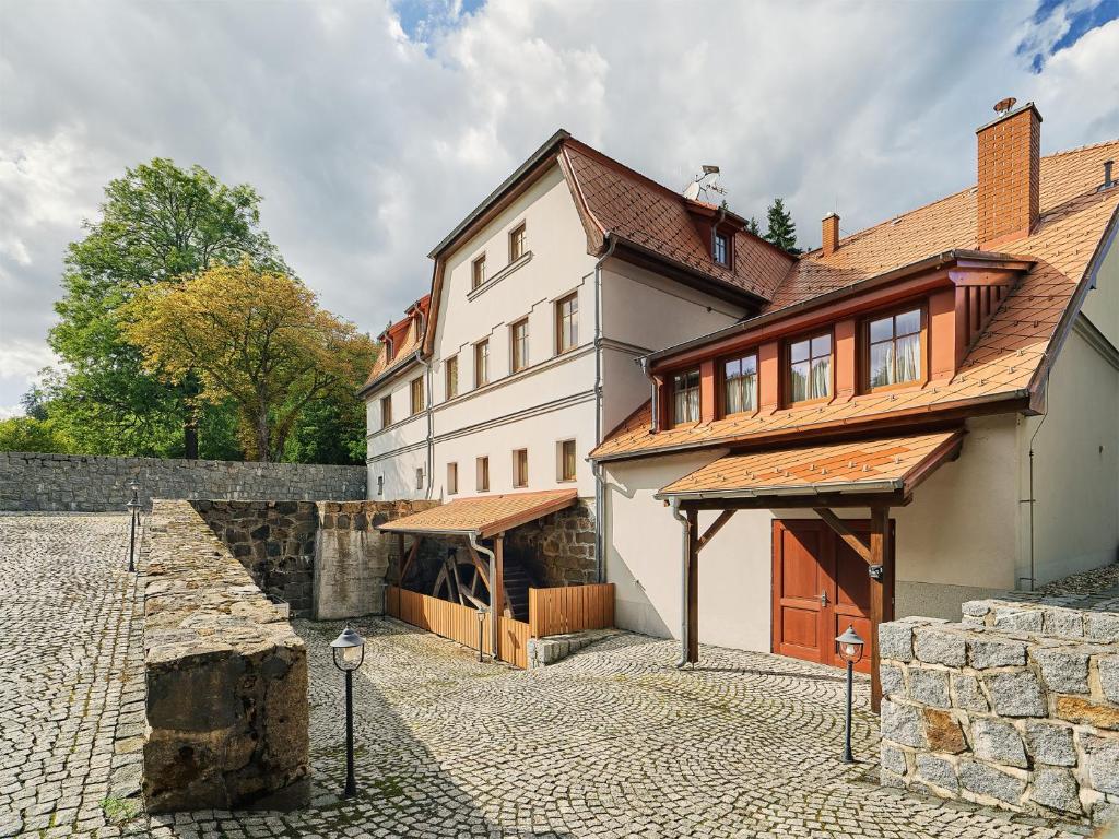 a large white house with a stone courtyard at Penzion Čítkův Mlýn in Šluknov