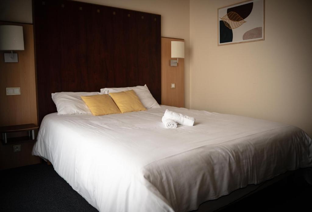 a large white bed with two towels on it at Logis Hôtel & Restaurant Le Cheval Blanc et Clovis in Vouillé