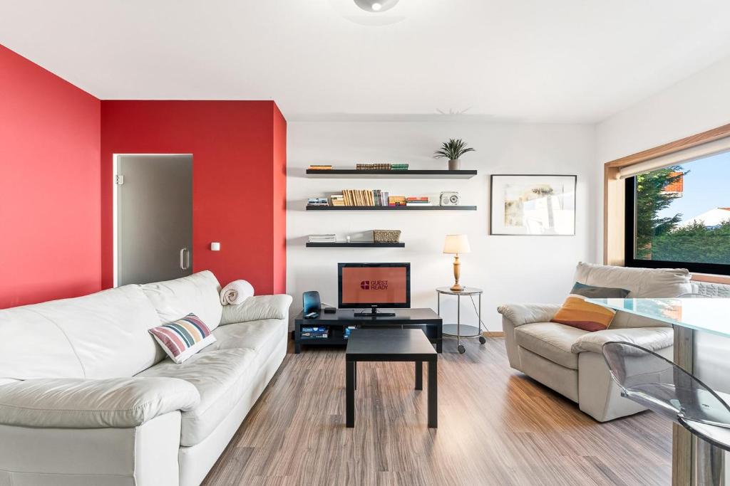 a living room with a red accent wall at GuestReady - Seaside Experience in Moledo in Moledo